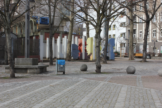 Foto Falkplatz, runde Bank beim Spielplatz mit Blickrichtung Skulpturen Köpfe, Rollbergsiedlung, Neukölln, Berlin (Foto: Kirsten Kötter)